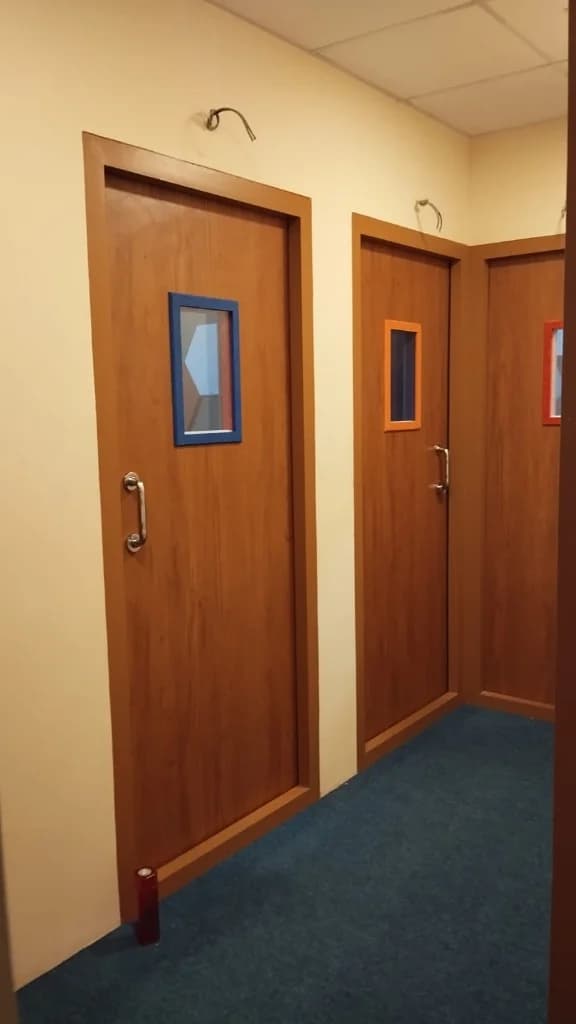 Color-coded studio booth doors along a technical facility corridor